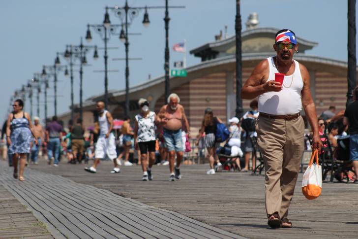 A photo of people walking on the Coney Island boardwalk on a hot day in June
